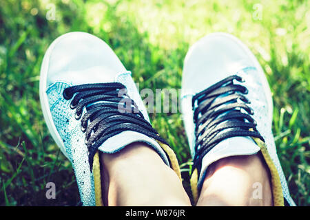 Giovane donna gambe nella coppia di scarpe sportive sneakers di blue suede sul prato in posizione di parcheggio Foto Stock