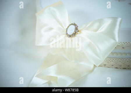 Large White silly nastro con un delicato cammeo spilla a copertura di un bianco estate boemo hat, vintage accessorio per una occasione speciale Foto Stock