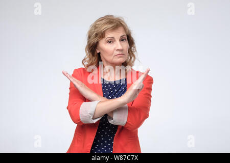 Matura donna caucasica accigliata attraversando bracci sul torace in rifiuto e vietare il gesto Foto Stock
