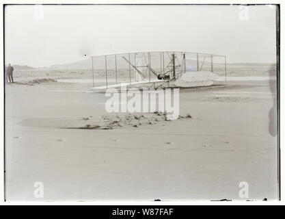 Vista ravvicinata del danneggiato 1903 Wright Flyer sul terreno dopo il suo quarto e ultimo volo su dicembre 17, 1903. Il flyer era atterrato il disco, rottura telaio del canale elevatore. Il Wrights aveva sperato di poter riparare rapidamente questo tipo di danni e di effettuare ulteriori voli di prova, ma un po' di tempo dopo che questa è stata scattata la foto, il Flyer è stato catturato e ribaltato da una raffica di vento, causando molto più gravi danni e di terminare la sua carriera di volo. Foto Stock