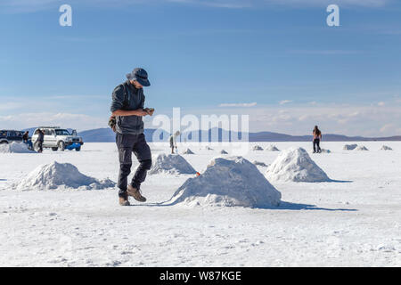 Uyuni distesa di sale di Uyuni, Bolivia : i turisti a piedi in bianco salar e godere di tour in jeep attività attraverso la guida Boliviana deserto di sale Foto Stock