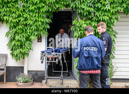 Bennigsen, Germania. 08 Ago, 2019. Due poliziotti a stare di fronte ad una casa in cui un uomo è detto di avere ucciso la sua fidanzata, mentre due imprenditori entrare in casa con una barella. Il 61-anno-vecchio uomo da Bennigsen vicino Hannover composto il numero di emergenza su 08.08 nel pomeriggio e ha detto alla polizia che aveva ucciso il 58-anno-vecchio. Credito: Christophe Gateau/dpa/Alamy Live News Foto Stock