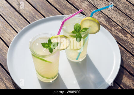 Due limonata fresca o cocktail mojito in vetro con paglia su una tavola di legno Foto Stock