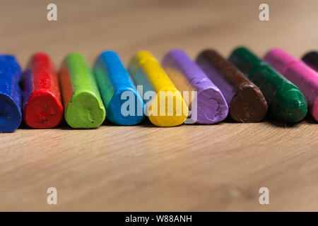 Diverse colorate le matite utilizzate in una fila su un sfondo di legno Foto Stock