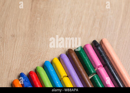 Diverse colorate le matite utilizzate in una fila su un sfondo di legno Foto Stock