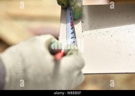 Falegnameria, mans mano utilizzando nastro di misurazione per misurare l'asse di legno e marcatura con matita Foto Stock