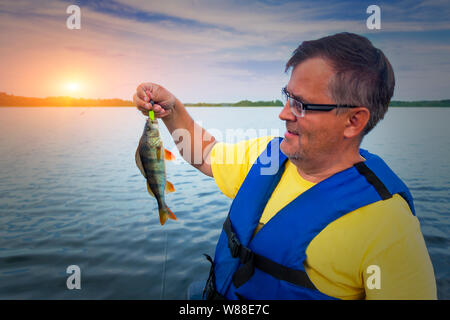 Un pescatore tiene una presa Foto Stock
