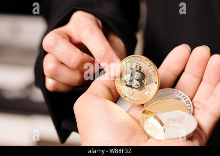 Cryptocurrency Bitcoin. Le donne ricoprono il cryptocurrency moneta sulla mano. Physical bitcoins moneta in oro Foto Stock