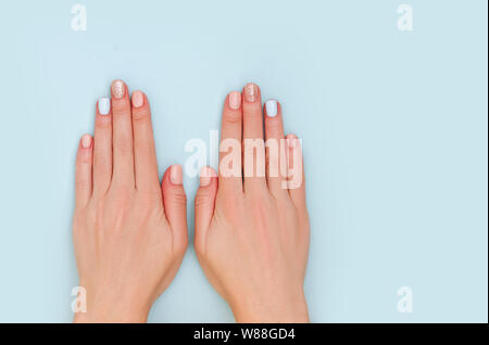 Donna con le mani manicure pastello su sfondo blu con una copia dello spazio. Foto Stock