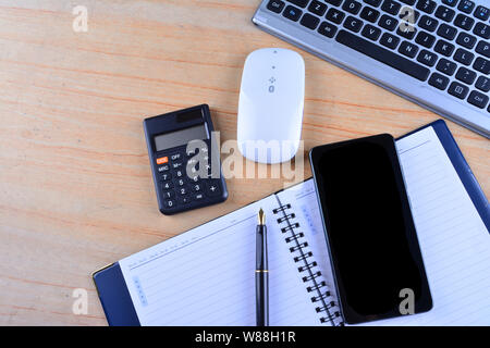 La tastiera con mouse, penna stilografica, notebook, calcolatrice e smartphone su un tavolo Foto Stock
