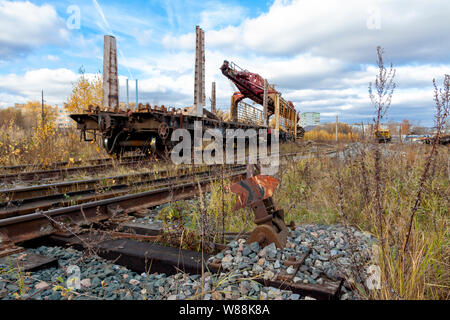 Una vecchia macchina di posa di binari ferroviari si trova su una vecchia linea ferroviaria abbandonata. Foto Stock