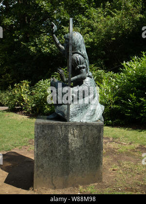 La scultura in bronzo di Alice guardando attraverso il Looking Glass da Jean Argent nel parco del Castello di Guildford, Surrey Foto Stock