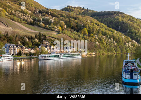 Vista a la città di Bernkastel-Kues al fiume Mosella con le navi da passeggeri e le montagne con vigneti in background Foto Stock