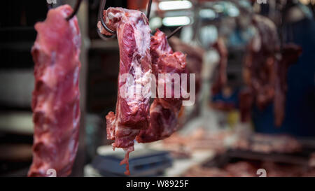 Vista dettagliata del crudo fresco di carne di maiale appeso a una pressione di stallo asiatici in vendita. Tradizionale negozio taiwanese di mercato in Taitung. Il mercato popolare di Taiwan. Vendita Foto Stock