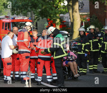 Amburgo, Germania. 08 Ago, 2019. Il personale dei servizi di emergenza e i residenti sono in piedi sulla strada durante un incendio in una casa di riposo. Nessuno è stato ferito in un grande incendio in una casa di riposo in Hamburg-Eidelstedt. I vigili del fuoco è stata in grado di ottenere circa 40 i pensionati della combustione edificio nel tempo. Il dipartimento dei vigili del fuoco è sul sito con più di 100 vigili del fuoco per combattere il fuoco. Credito: Bodo segna/dpa/Alamy Live News Foto Stock