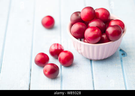Il red cherry prugne frutta sul tavolo blu. Foto Stock