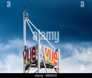 Vue Cinema segno Logo illuminato dal sole contro un cielo nuvoloso scuro Foto Stock