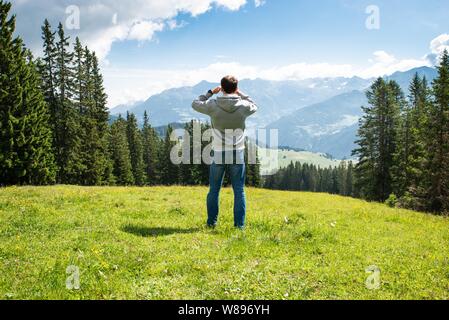 L'uomo gode di vista panoramica sulla montagna a giornata di sole Foto Stock