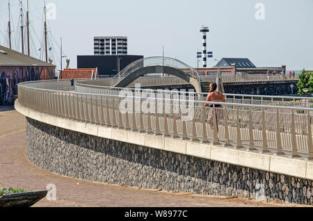 Harlingen, Paesi Bassi, 26 Luglio 2019: la difesa costiera parete, completata nel 2010, combinato con una passeggiata pedonale su una soleggiata giornata estiva Foto Stock