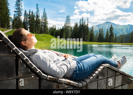 Donna rilassante in prendisole vicino al Lago in montagna Foto Stock