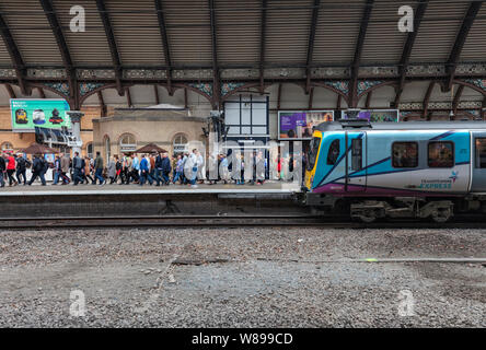 Passeggeri ferroviari lasciando un primo transpennine Express classe 185 presso la stazione ferroviaria di York, che stava lavorando a Newcastle a Manchester il treno Foto Stock