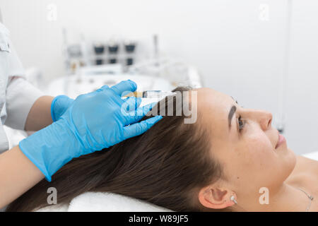 Estetista iniezioni per una sana crescita dei capelli. La mesoterapia del cuoio capelluto. Una giovane ragazza sta subendo un corso di trattamenti termali in ufficio di un beau Foto Stock