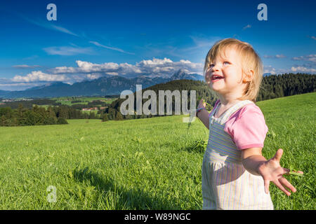 In Germania, in Baviera, Allgaeu, Happy Baby girl giocando nei campi Foto Stock