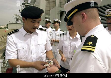 Stati Uniti Navy tenente j.g. Bruce Sutherland (destra) dà Capt. Wen Hai Wu (sinistra) dell Esercito di Liberazione del Popolo (Marina) U.S. Navy officerХs crest come un segno di apprezzamento e di buona volontà durante la visita di porta della USS Chancellorsville (CG 62) a Qingdao, Cina, il 3 agosto, 2000. Wu e altri membri di equipaggio della nave da guerra cinese Haerbin una serie di concerti (DDG 112) sono lo scambio di visite con equipaggio di Chancellorsville mentre la classe Ticonderoga, Aegis missile cruiser visite Qingdao. Foto Stock