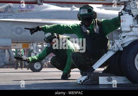 Stati Uniti Navy Petty Officer di terza classe Jeffrey Bedsole (sinistra) e Airman Mario Wright dare il segnale per un aeromobile di taxi in avanti sul ponte di volo della USS John C. Stennis (CVN 74), il 3 agosto, 2004. La Stennis e la sua avviato Carrier aria Wing 14 sono in mare che partecipano a una distribuzione programmata e il supporto di impulso di estate 2004, una marina esercizio dove sette aerei sciopero portante gruppi sarà imparare nuovi modi di operare, formazione di equipaggio e mantenendo la loro flotta. Foto Stock