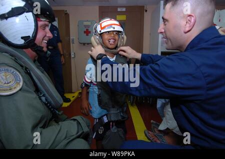 Chief Petty Officer Patrick Nordulli (destra) e sottufficiali di seconda classe Jeffery Moore (sinistra) preparare dimesso paziente indonesiano Wahyu Firmandao per un volo in elicottero a terra dal fissaggio della cinghia per il mento sul suo casco craniale, a bordo della marina militare nave ospedale USNS misericordia (T-AH 19), il 14 febbraio, 2005. La misericordia è in funzione al largo di Banda Aceh, Sumatra, Indonesia, per fornire assistenza medica e di soccorso in caso di catastrofe per il popolo dell Indonesia colpite dal devastante tsunami che ha colpito il Sud Est asiatico del 26 dicembre, 2004. Firmandao è stato il primo paziente indonesiano trattati a bordo di misericordia per un perf Foto Stock