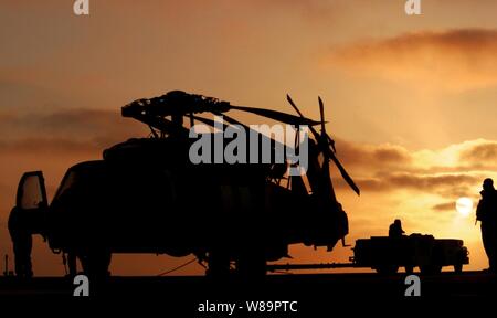 Stati Uniti I marinai della marina preparare un taxi per una SH-60S Seahawk elicottero attraverso il ponte di volo a bordo della portaerei USS Ronald Reagan (CVN 76) all'alba del 12 maggio 2005. Il Reagan è in corso di svolgimento routine di condurre le operazioni di carrier nell'Oceano Pacifico. Foto Stock