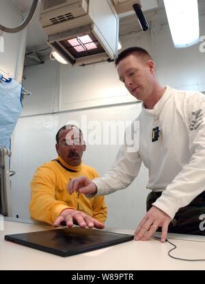 Navy Petty Officer 1. Classe Troy Murphy (a destra) prepara una mano del paziente per un X-ray a bordo della portaerei USS Theodore Roosevelt CVN (71) il 4 aprile 2005. Murphy è un ospedale Navy corpsman. La portaerei e la sua avviato Carrier aria Wing 8 sono la formazione, mentre in corso nell'Oceano Atlantico. Foto Stock