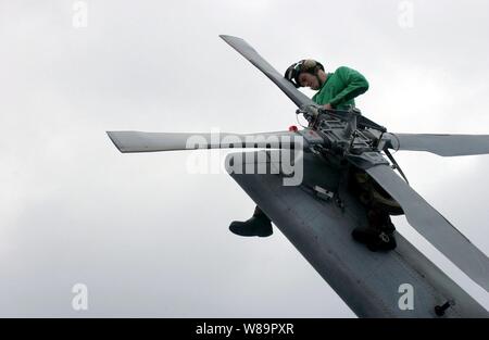 Petty Officer di terza classe Adam Barbiere posatoi sulla coda di una SH-60F Seahawk come egli sostituisce l'elicottero di anti-urto leggero a bordo della portaerei USS Nimitz CVN (68) il 10 giugno 2005. Il barbiere è un Navy Aviation da elettricista, Mate assegnato all'elicottero Anti-Submarine Squadron 6 distribuito a bordo della Nimitz dalla Naval Air Station North Island, San Diego, California Foto Stock