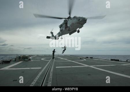 Un U.S. Navy HH-60H Seahawk elicottero si libra sul ponte di volo di HMAS Canberra (FFG 02) come mentre Adm posteriore. Jamie D. Kelly, comandante del Carrier Strike gruppo 5, rappels al ponte del 7 giugno, 2005. Kelly è in visita a Canberra prima della portaerei USS Kitty Hawk's (CV 63) partecipazione in esercizio talismano Saber, una biennale forze congiunte e di esercizio combinato con la Marina australiana. Foto Stock