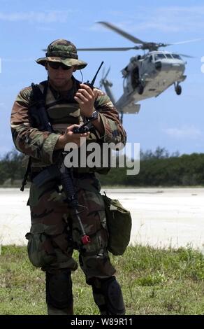 Navy Petty Officer 2a classe Jackson J. Stasny ascolta una chiamata sulla sua radio come un MH-60S elicottero si prepara a terra durante un esercizio presso la base navale di Guam, Santa Rita, Guam, il 30 giugno 2005. Stasny è con la Mobile Security Squadron 7 distacco 73, che è in corso la sua pre-esercizi di certificazione prima di essere ufficialmente esaminate per determinare se può essere certificato per l'installazione. Foto Stock