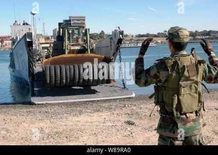 Petty Officer di terza classe Guadelupe Rivera dirige il driver di U.S. Bulldozer marino off di una landing craft al Del Mar bacino in barca a Camp Pendleton, California, il 5 dicembre, 2005. Il Landing Craft è il trasporto di marines della xi Marine Expeditionary Unit e le loro attrezzature da assalto anfibio nave USS Peleliu (LHA 5) a Camp Pendleton. Peleliu è in corso al largo della costa della California del Sud per esercitazioni navali in preparazione per la sua prossima distribuzione. Foto Stock