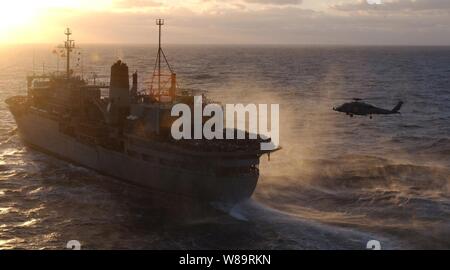 Una Marina HH-60H Seahawk elicottero calci fino a cortina di spray come si avvicina il ponte di volo della lotta contro i negozi nave USNS Spica (T-AFS 9) durante un rifornimento verticale con la portaerei USS Theodore Roosevelt (CVN 71) Febbraio 28, 2006, nel mar Mediterraneo. Foto Stock