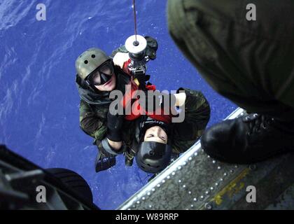 L'eliminazione degli ordigni esplosivi nuotatori Petty Officer 2a classe Ryan Swanson (sinistra) e il tenente John Laney sono sollevati in una SH-60F Seahawk elicottero durante la colata e operazioni di recupero nell'Oceano Pacifico il 10 marzo 2006. Swanson e Laney sono allegate per l'eliminazione degli ordigni esplosivi distacco 9. Foto Stock