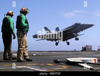 Ponte di volo equipaggio guardare come un F/A-18E Hornet esegue un tocco e passare il ponte di volo della USS Abraham Lincoln (CVN 72) il 6 giugno 2005. La Nimitz-aeromobili di classe carrier e Carrier aria Wing 2 stanno attualmente conducendo la disponibilità alla formazione nell'Oceano Pacifico. La Hornet è attaccato a Strike Fighter Squadron 137 del Naval Air Station Lemoore, California Foto Stock