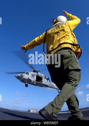 Un U.S. Marina ponte di volo crewman segnali al pilota di un MH-60S Seahawk elicottero verticale durante le operazioni di rifornimento sul ponte di volo della portaerei USS Theodore Roosevelt CVN (71) mentre è in corso nell'Oceano Atlantico il 5 febbraio, 2008. Il Seahawk è assegnato ad un elicottero di combattimento squadrone di supporto 26. Foto Stock