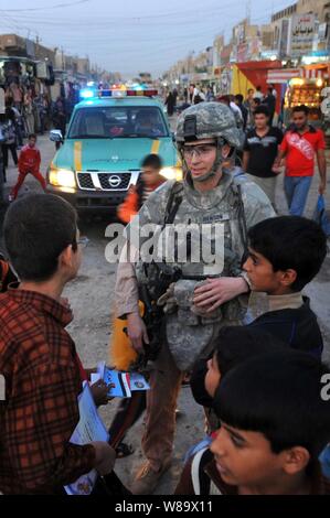 Stati Uniti Air Force 1 Lt. Steven Benson parla con bambini iracheni durante una pattuglia di polizia irachena nel mercato Shurta del Al-Bayaa distretto di Baghdad, Iraq, su nov. 14, 2008. Il aviatori sono assegnati ad un distacco 3, 732nd Expeditionary forze di sicurezza Squadron e sono fissati al 1° Brigata Team di combattimento, 4a divisione di fanteria. Foto Stock