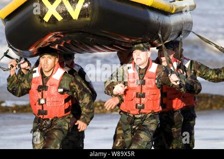 Stati Uniti Navy base demolizioni subacquee/tenuta agli studenti di corsa giù in spiaggia durante il loro primo Surf evoluzione di passaggio presso la Naval Special Warfare Center a Naval Amphibious Base Coronado, California, a gennaio 27, 2009. Foto Stock