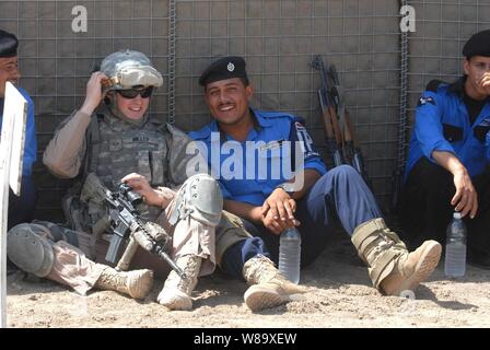 Stati Uniti Air Force Senior Airman Miller, attaccato al ruvido Riders, 91º Battaglione, Task Force Dragon, rilassa con un gruppo di poliziotti iracheni a un poligono di tiro in Mahmudiyah, Iraq, il 23 aprile 2009. La ruvida piloti sono istruire poliziotti iracheni in modo sicuro il compito e il fuoco le loro armi. Questi poliziotti saranno inviati per istruire gli altri poliziotti iracheni in tutto il paese. Foto Stock