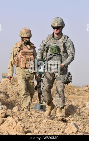 Un U.S. Soldato dell'esercito con il primo plotone, Comanche truppa, 1° Stormo, 150° reggimento di cavalleria, trentesimo Heavy Brigade Combat Team, 1a divisione di cavalleria aiuta a soldati iracheni con 1° Company, 3° Battaglione, XXIII brigata, xvii divisione irachena di armi condurre ricerche cache attraverso campi aperti nell'area Radwaniyah fuori Baghdad, Iraq, il 18 luglio 2009. Foto Stock