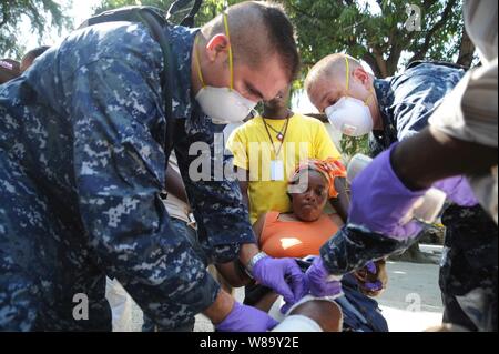 Stati Uniti Navy Lt. Marlin Williams, un cappellano e sottufficiali di prima classe Kishman Adam, un ospedale corpsman, assegnato alla portaerei USS Carl Vinson (CVN 70) trattare una vittima di masterizzazione a Killick Coast Guard Base in Carrefour, Haiti, a gennaio 18, 2010. Il personale medico a Killick stanno dando il primo soccorso e cure primarie di trattamento nel supporto di uragano aiuto in caso di catastrofe. Foto Stock