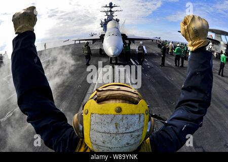 Un aeromobile direttore guida una F/A-18C Hornet su una catapulta a bordo della portaerei USS Harry Truman (CVN 75) nell'Oceano Atlantico il 1 febbraio 2011. L'Harry Truman è sostenere la sostituzione della flotta squadrone qualifiche portante. Foto Stock