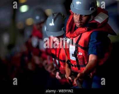 Stati Uniti I marinai della marina uomo una linea nell'hangar bay a bordo della portaerei USS Carl Vinson (CVN 70) durante un rifornimento in mare Arabico nel febbraio 25, 2011. Foto Stock