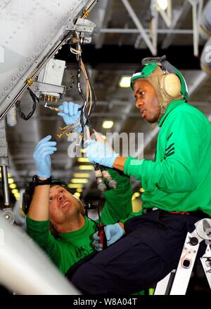 Petty Officer di prima classe William Schuyler (destra) e sottufficiali di prima classe Jason Siani, entrambi assegnati alla elicottero Anti-Submarine Squadron 4, riparare i componenti di un radar warning system su un elicottero in hangar bay a bordo della portaerei USS Ronald Reagan (CVN 76) nell'Oceano Pacifico il 16 aprile 2011. Foto Stock