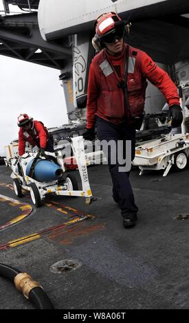 Petty Officer di 2a classe di Jeffrey Anderson (destra) e sottufficiali di prima classe Michael Washa spostare inesplosi sul ponte di volo della portaerei USS John C. Stennis CVN (74) nell'Oceano Pacifico il 13 maggio 2011. John C. Stennis Carrier Strike Group partecipa a una formazione composita dell'unità esercizio al largo della costa della California del sud. Foto Stock