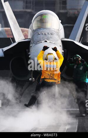 Stati Uniti Navy Petty Officer 2a classe Ryan Hilliard guida una F/A-18C Hornet aeromobile assegnati alle Marine Fighter Attack Squadron 323 verso una navetta catapulta sul ponte di volo della portaerei USS Ronald Reagan (CVN 76) nel Golfo Persico il 15 maggio 2011. Il Ronald Reagan e Carrier aria Wing 14 sono distribuiti negli Stati Uniti Quinta Flotta area di responsabilità condurre aria vicino le missioni di sostegno. Foto Stock